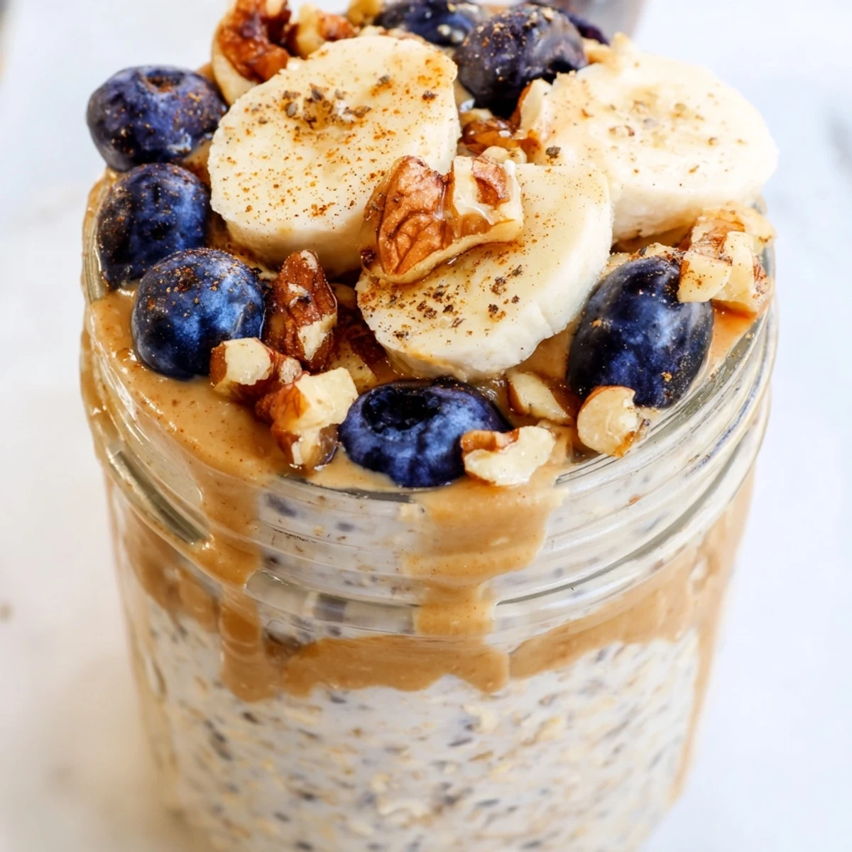 Thick vanilla protein overnight oats served in a jar with sliced banana