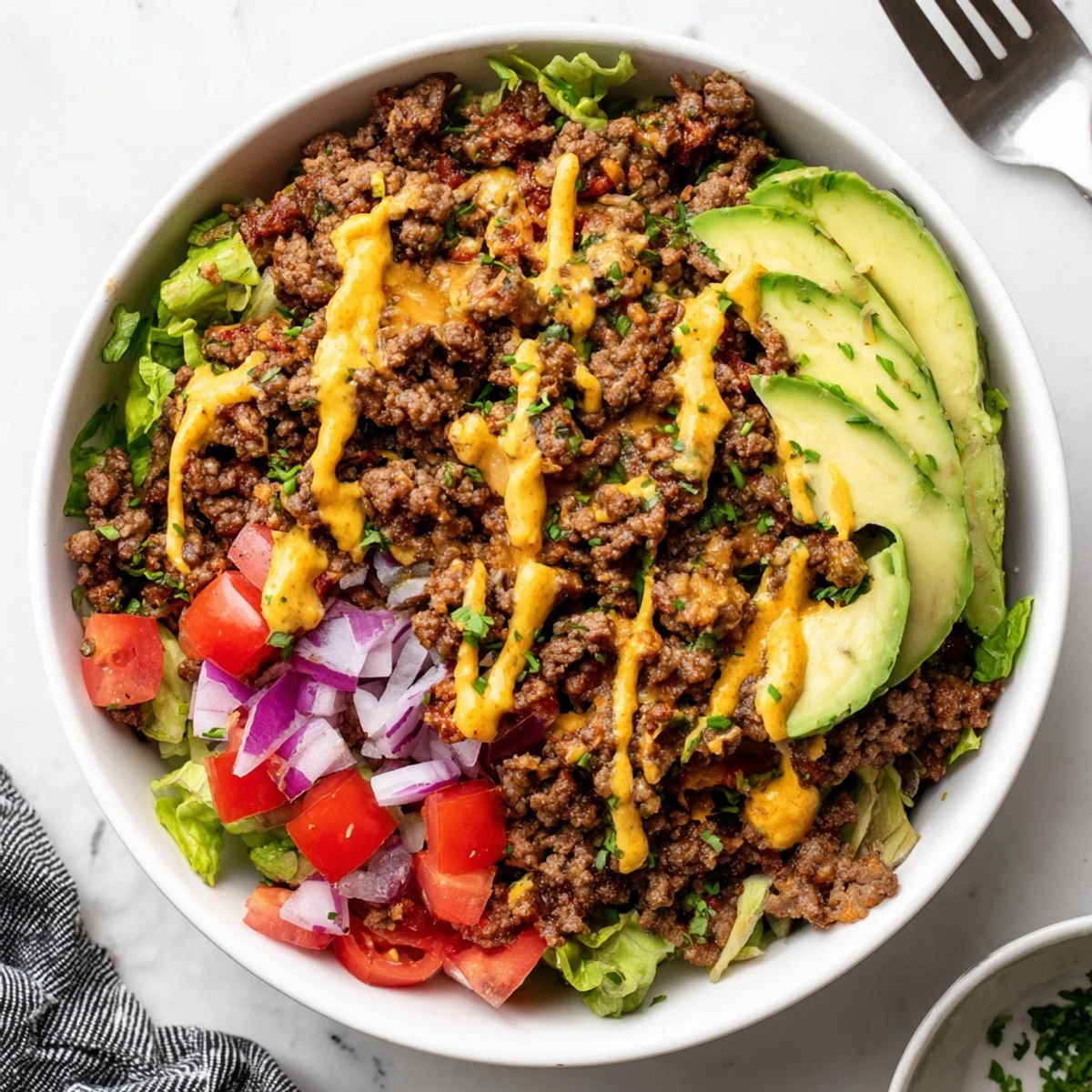 Juicy ground beef burger bowls topped with avocado, pickles, and tangy sauce