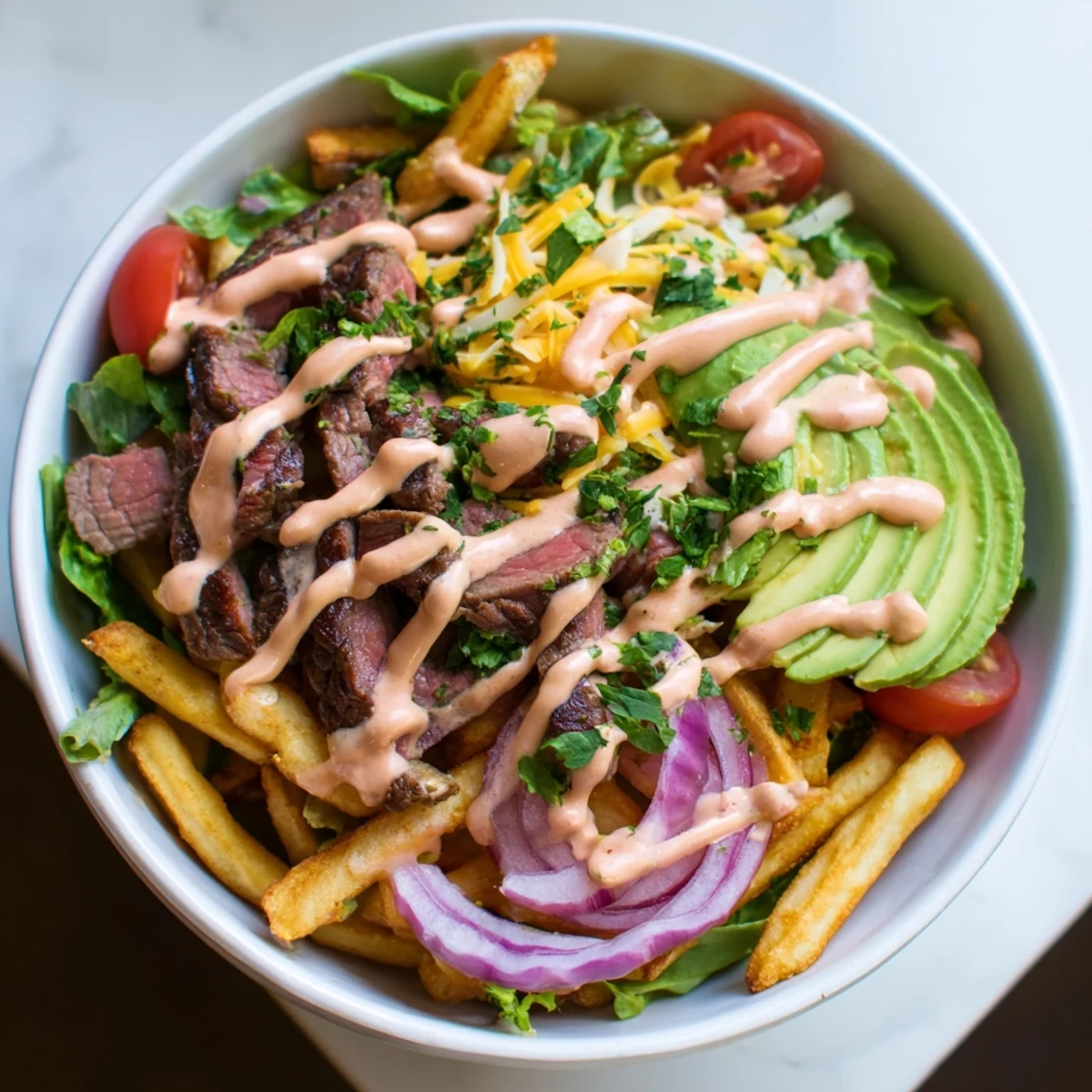 Tender juicy steak strips nestled beside crunchy fries and colorful vegetables in a comforting bowl