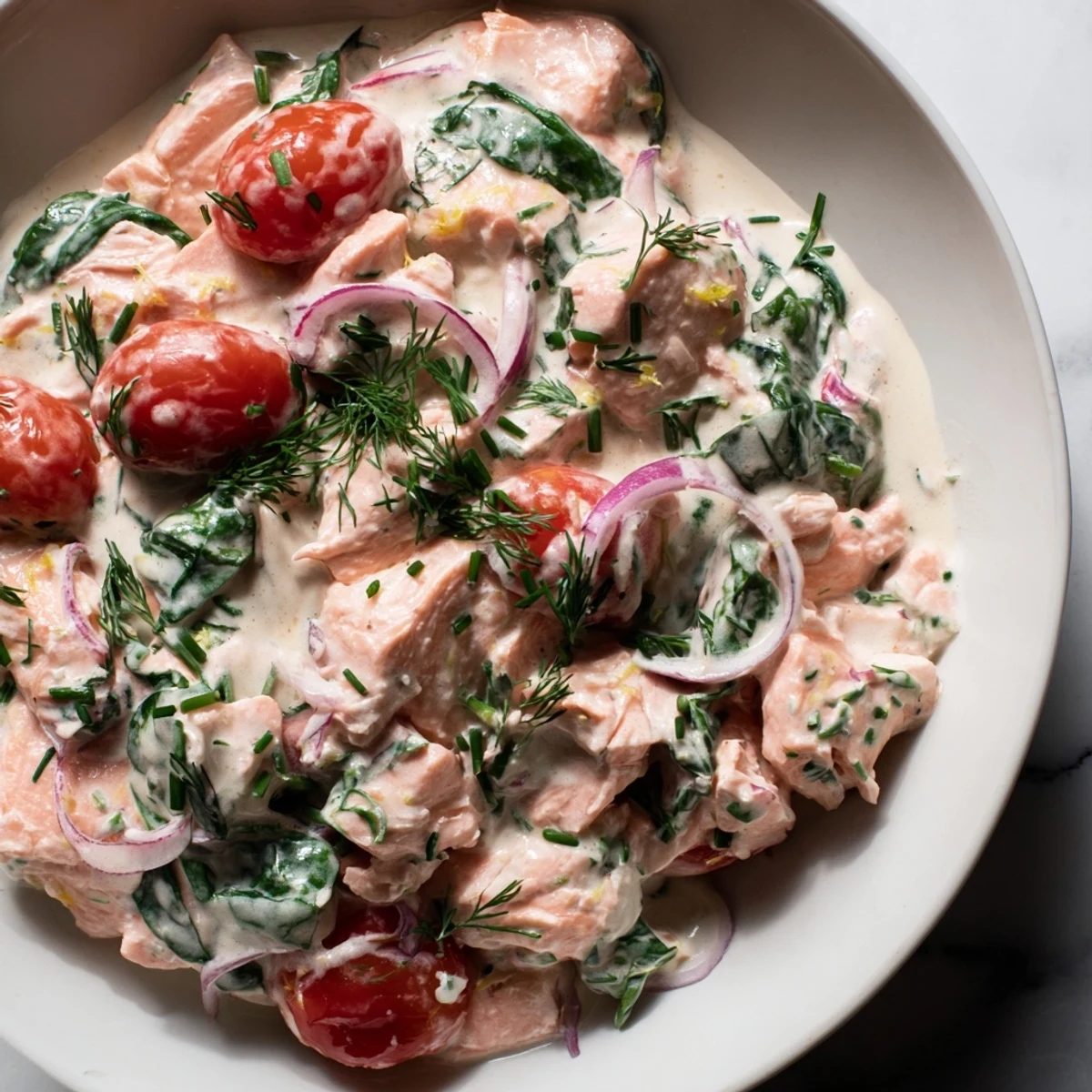 Creamy leftover salmon recipe plated with wilted spinach and juicy tomato halves