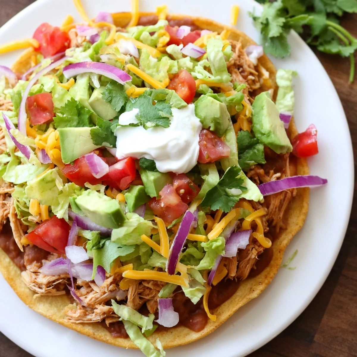 Heaps of seasoned chicken on crunchy tostada shells with vibrant tomatoes and sliced avocado.  