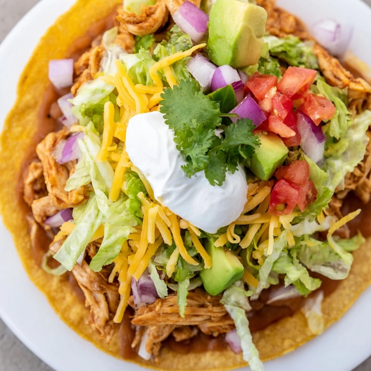 Delicious Chicken Tostadas piled high with colorful veggies, melted cheese, and zesty lime wedges.