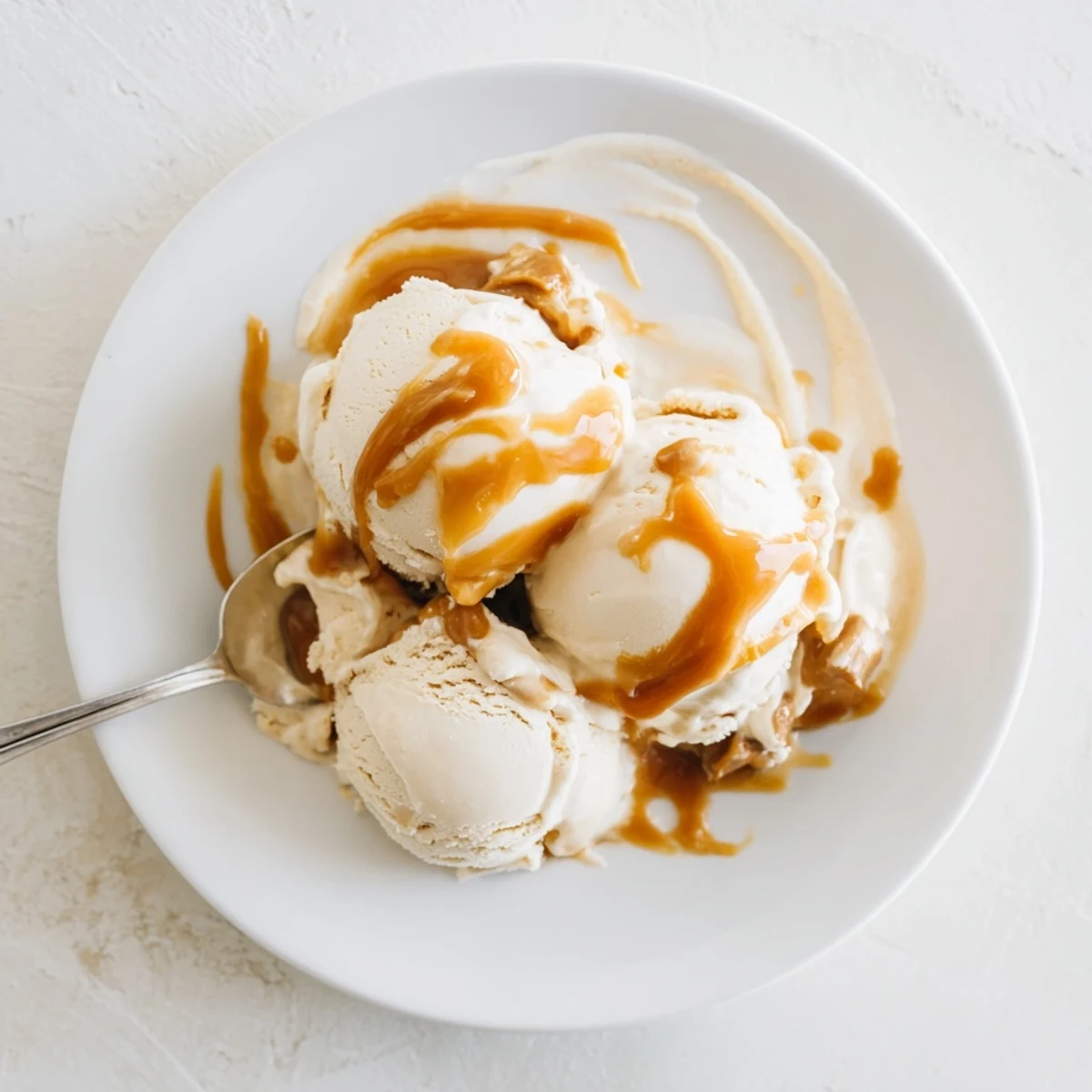 Scoop of smooth no churn salted caramel ice cream recipe drizzled with extra sauce.  