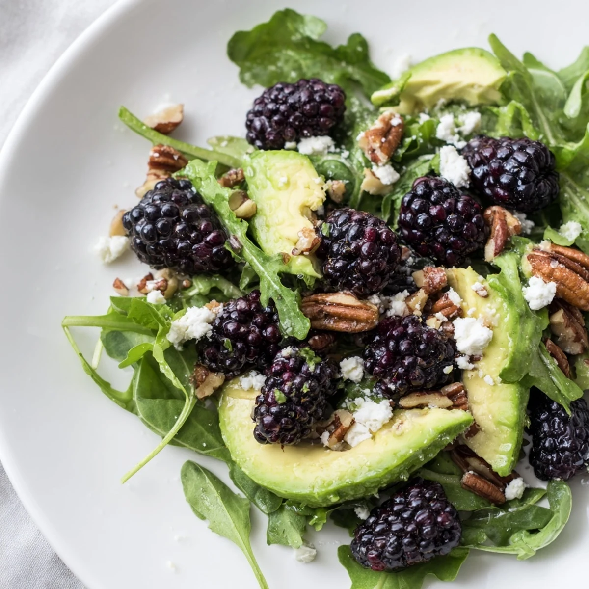 Refreshing Blackberry Avocado Salad drizzled with zesty honey-lime dressing on arugula