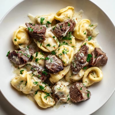 Golden steak pieces nestled beside plump cheese tortellini drenched in a velvety garlic cream sauce