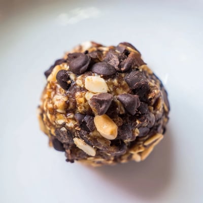Bite-sized Snickers energy balls showing creamy peanut butter and dark chocolate layers.